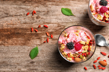 Delicious dessert with goji berries in glass on wooden background