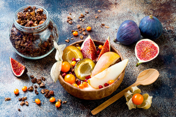 Fall breakfast bowl with chocolate granola, coconut yogurt and autumn seasonal fruits and berries....
