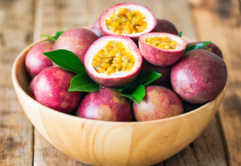 Passion fruit on wood bowl put on wood table in vintage tone style for background or wallpaper. Ripe passion fruit so sweet and sour. Passion fruit is tropical fruit. - obrazy, fototapety, plakaty