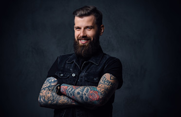 Studio portrait of bearded hipster male with tattoos on his arms.