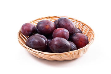 Yellow wooden basket with ripe plums isolated on a white background..