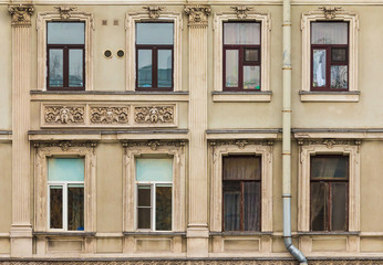 Several windows in a row and balcony on facade of urban apartment building front view, St. Petersburg, Russia