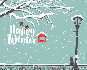 Fototapeta premium Vector winter scene at the snow-covered park with calligraphic inscription Happy Winter, with branches of a tree, bullfinches and a bird feeder, a street lamp and a cat on the fence in the snow