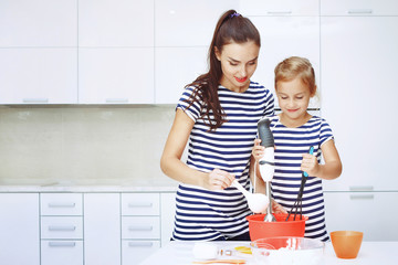 Smiling mother and daughter on a beautiful white kitchen dough blender knead