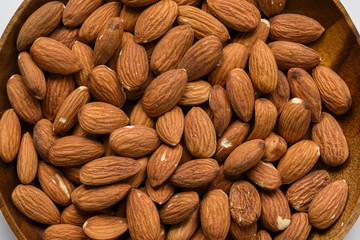 Top view dried almond in wood bowl on white background.