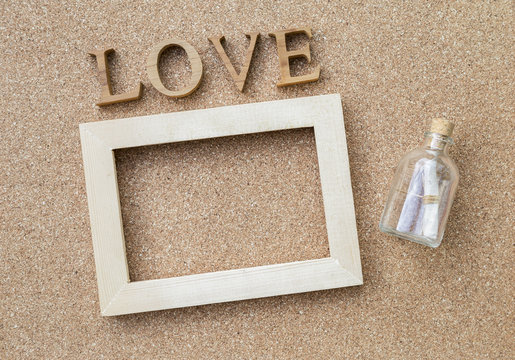 Love message, message bottle and wooden frame with love text on corkboard background