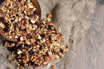 Homemade granola spilling from bowl on wooden table
