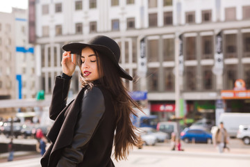 Fototapeta premium Moda portret młodej ładnej modelki nosi kapelusz z szerokim rondem. Pani pozowanie na tle alei
