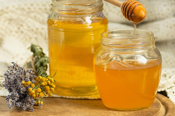 Honey in the glass jar is beside the attributes