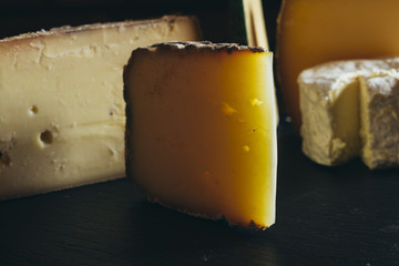 Cheese assortment on black background. Various sorts of cheese for appetizing, gourmet, delicious snacks. Traditional French dish served with wine for lunch and dinner. Closeup. Toned
