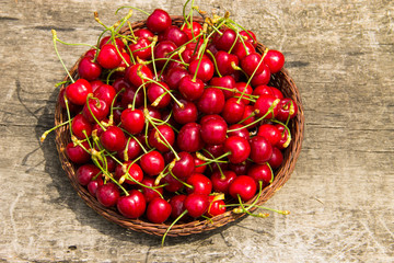 Basket with red sweet cherry fruits on vintage wooden table. Summer fruit season concept