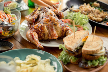 Grilled chicken are placed on the table with foods.