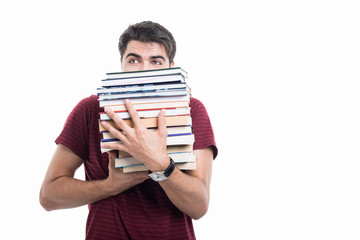 Handsome student posing hiding behind pile of books