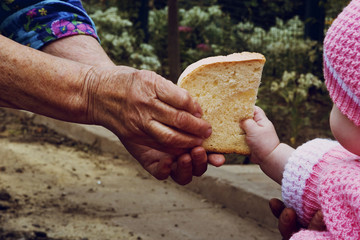 An old grandmother gives a piece of bread to a small child