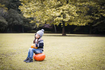 Fototapeta premium Little girl sitting on the pumpkin