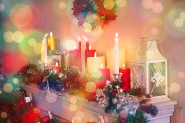 Candles and christmas decorations arranged on fireplace