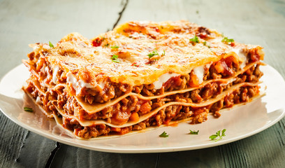 Slice of delicious beef lasagne on a plate - obrazy, fototapety, plakaty