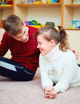 Smiling Teenage Friends With Special Needs Talking Cheerfully Together In Rehabilitation Center