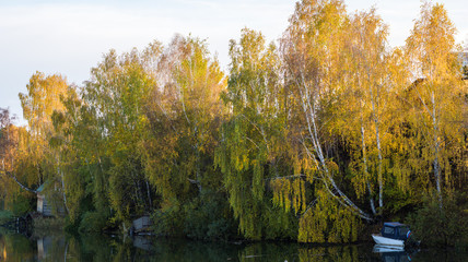 Obraz premium Autumn landscape on the river in the evening. Boat on the shore.