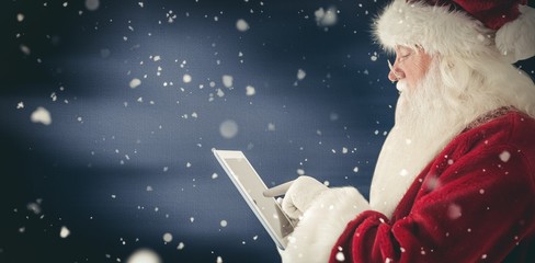 Composite image of santa uses a tablet pc