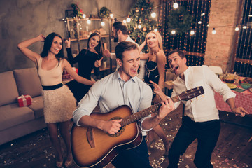 Celebrating newyear. Young handsome musician makes a noise with his instrument! Group of beautiful...