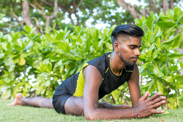 Naklejka na ściany i meble Young yoga man practitioners doing yoga on nature. Asian indian yogis man on the grass in the park. Bali island.