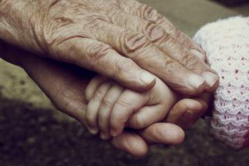 Baby hands in old wrinkled hands of grandmother