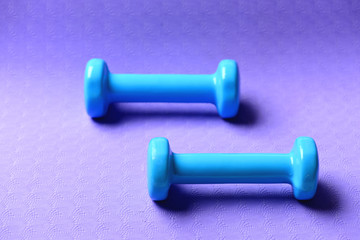 Dumbbells in cyan blue color on purple background