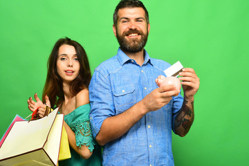 Man with beard holds credit card and piggy bank