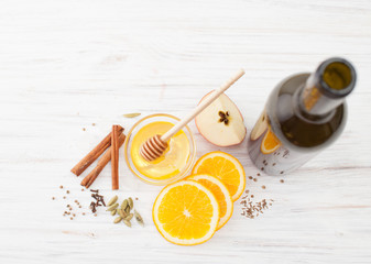 A bottle of wine, slices of orange, honey, cinnamon to mulled wine on white