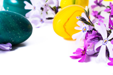 close-up of colorful easter eggs and phlox flowers on white background with copy space. border template, easter greeting and holiday card.