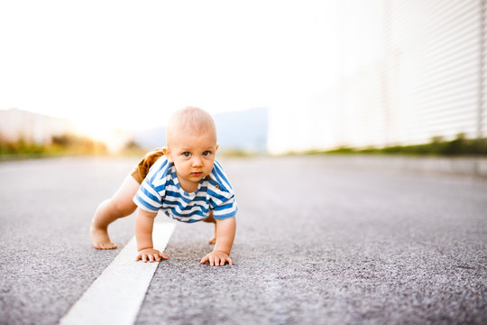 Little baby boy crawling outside on the road.