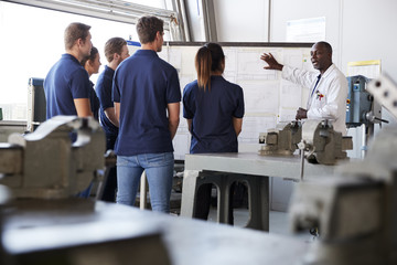Engineering apprentices watching presentation at whiteboard