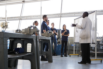 Engineering apprentices stand at a training presentation, low angle