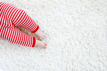 Close-up of baby body and legs in red Santa Clause trousers on Christmas