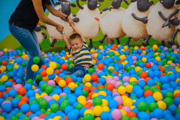 A boy with mother in the playing room with many little colored balls