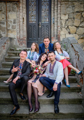 Fototapeta premium Pretty people in embroidred clothes sit before old stone building