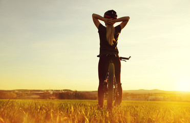 Girl on a bicycle in the sunset. Healthy lifestyle concept.