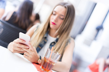 Pensive blonde teenager outdoor with her mobile phone