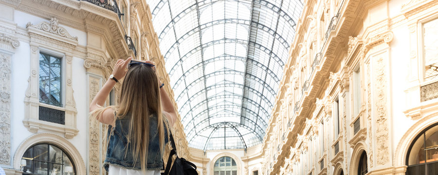 Pretty tourist teenager taking a photo with her mobile phone in the Vittorio Emanuele shopping arcade in Milan, Italy