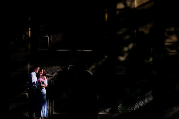 Fototapeta na wymiar Smiling couple stands in the spot of light in a darkness