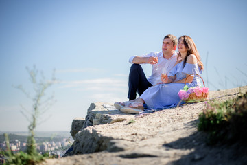 Fototapeta premium Charming couple sits with glasses of champagne on the rock