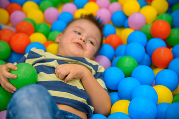 A boy in the playing room with many little colored balls
