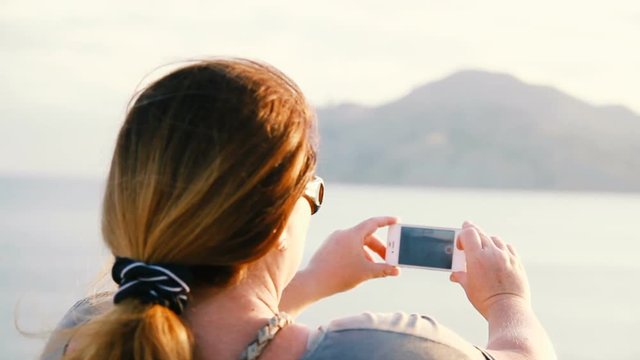 woman takes a photo of the landscape on the phone