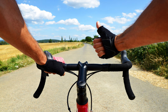 Hands in gloves holding handlebar. Cyclist rides on a road bike.