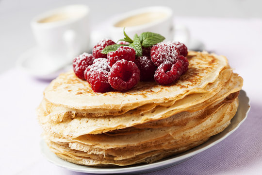 Stack of Russian-style pancakes with raspberries