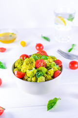 Salad Bowl with cherry tomatoes, boiled broccoli, basil and fresh ingredients on the white wooden background. Healthy lifestyle concept. Detox, diet, vegitarian. Selective focus. Space for text.
