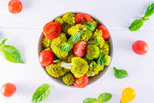 Top view Salad Bowl with cherry tomatoes, boiled broccoli, basil and fresh ingredients on the white wooden background. Healthy lifestyle concept. Detox, diet, vegitarian. Selective focus. Text space.