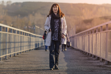 woman walking at sunset on a pedestrian bridge with handrails