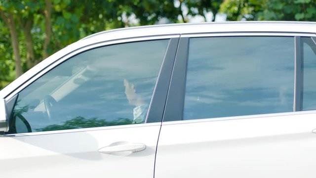 close up of Asian man driving a car to a stop outdoor
